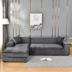 a living room with a gray couch and gold accents on the wall, along with a grey rug