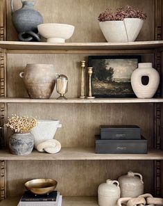 shelves with vases, books and other items on top of them in a room