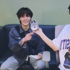 two young men sitting on a couch one holding a stuffed animal and the other smiling