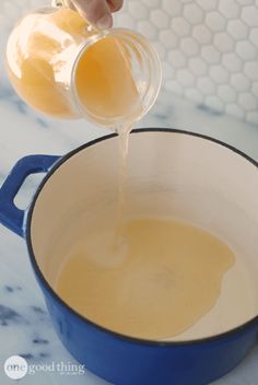 someone pouring eggs into a blue pot on a counter top with honey in the bowl