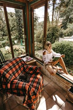 a woman sitting on a window sill reading a book