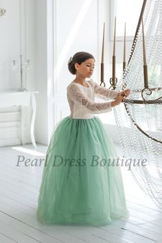 a woman in a long green skirt holding a chandelier