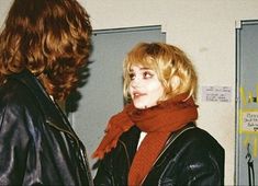 a man and woman standing next to each other in front of lockers with writing on them