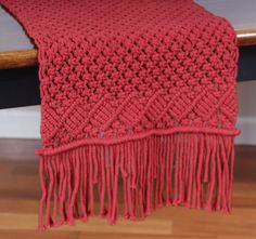 a red knitted blanket sitting on top of a wooden table next to a chair