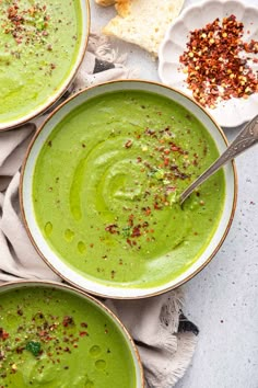 three bowls filled with green soup on top of a table