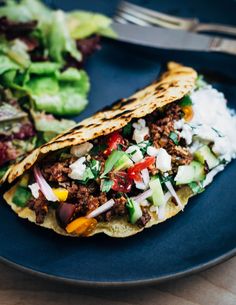 a taco on a plate next to a salad