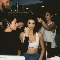 a woman getting her make - up done in front of two other women at a party