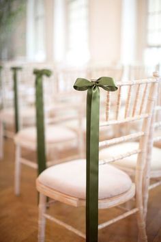 the chairs are decorated with green ribbons and bowes for guests to sit down in