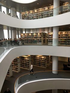 the interior of a library with many bookshelves and people walking around it,