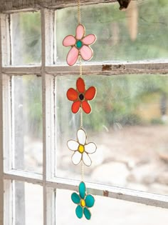 three colorful glass flowers hanging from a window