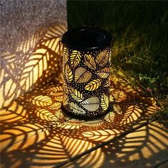 a black and yellow lantern sitting on top of a grass covered ground next to a wall