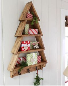 a wooden christmas tree shelf with presents hanging from it's sides on the wall