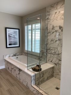 a bathroom with marble walls and flooring next to a bathtub in the corner