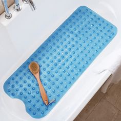 a wooden spoon sitting on top of a bath tub next to a blue mat with circles