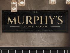 a sign that says the murphy's game room hanging from a wall with lights above it