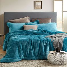 a bed with blue comforters and pillows in a bedroom setting on a carpeted floor