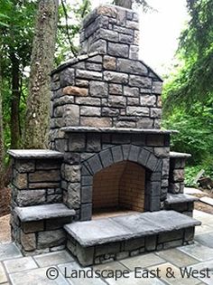 an outdoor fireplace in the middle of a wooded area with stone steps and benches around it