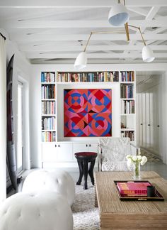 a living room filled with furniture and bookshelves next to a painting on the wall