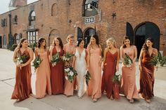 a group of women standing next to each other in front of a brick building holding bouquets