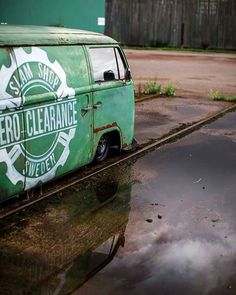 an old green van parked on the side of a road in front of a building