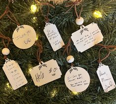 christmas ornaments are hanging on the tree with name tags attached to each ornament