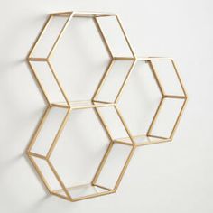 three hexagonal shelves are hanging on the wall, one is made out of gold metal