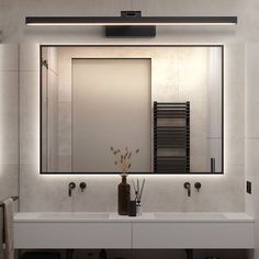 a bathroom with two sinks and a large mirror above the sink is lit by lights