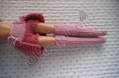 two dolls are wearing knitted mittens on a white surface, one is pink and the other is brown