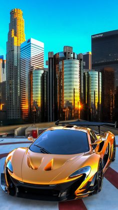 an orange sports car parked in front of a cityscape with skyscrapers behind it