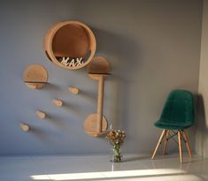 a green chair sitting in front of a wall with wooden sculptures hanging from it's sides