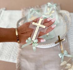 a woman's hand holding a small cross on top of a table