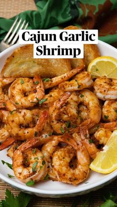 a white plate topped with shrimp next to lemon wedges and garnished with parsley