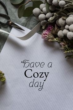 a piece of paper with the words have a cozy day on it next to flowers and scissors