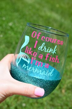 a hand holding up a wine glass that says off course i drink like a fish, ima mermaid