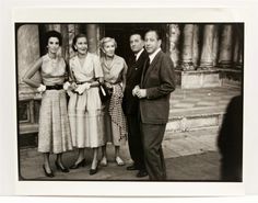 a group of people standing next to each other in front of a stone building with columns