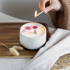 a person lighting a candle on a tray