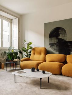 a living room filled with furniture and a large painting on the wall above it's windows