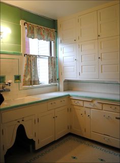 an empty kitchen with white cabinets and green counter tops is seen in this image from the front