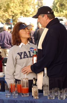 a man and woman standing next to each other at a table with glasses on it