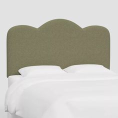 an upholstered headboard with white sheets and pillows