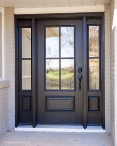 a black front door with two sidelights and glass panels on the top half of it