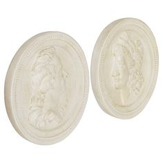 two white marble medallions depicting the head of a woman and a man with long hair