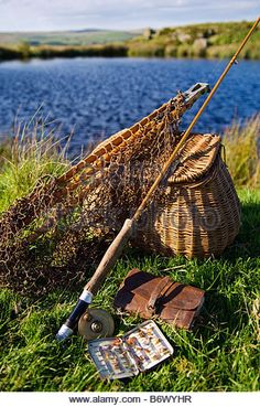 fishing gear on the bank of a river with a basket and fish hook in it