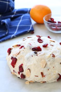 a doughnut with cranberries and almonds on it next to an orange