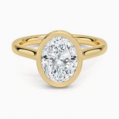 an oval shaped diamond ring in yellow gold with a center stone on the band and shoulders