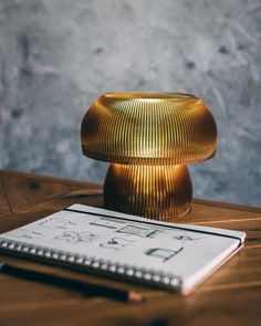 a table with a notebook, pen and lamp on it