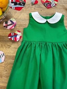 This classic, green cotton dress features a gathered skirt and white Peter Pan collar. Dress closes in the back with button closures.  Dress is made to order. Pinafore apron not included. **I have one ready-to-ship size 3t available directly on website here: https://wolfbanditpupbrigade.com/products/classic-green-dress-with-peter-pan-collar-sample-size-3t Cotton A-line Dress With Box Pleat, Classic Green Cotton Dress, Classic Green Spring Dress, Classic Cotton Dress For Dress-up Occasions, Classic Cotton Dresses For Dress-up, Classic Cotton Dresses For Dress-up Occasions, Green Cotton Dress For Dress-up, Cotton Dress With Peter Pan Collar For Garden Party, Green Cotton Dress