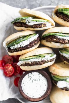 several sandwiches with cucumbers and cream cheese on them next to some tomato slices