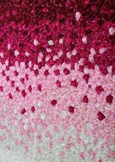 pink and white crocheted wall hanging on the side of a building with flowers in it