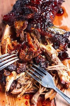 barbecue ribs with bbq sauce on a wooden cutting board next to a knife and fork